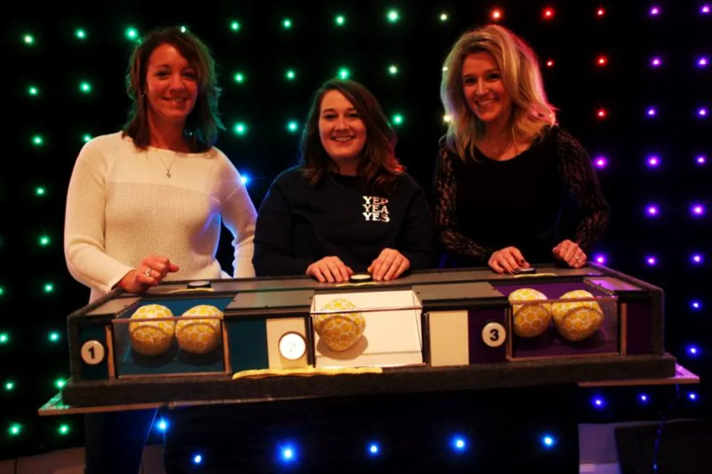 Three corporate guests at a Have-A-Ball game show podium under colored lights